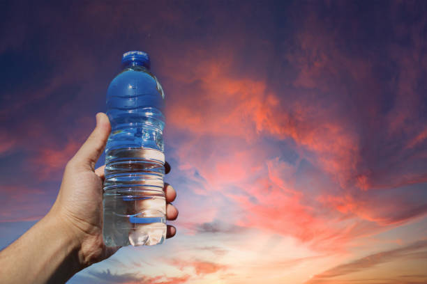 istock water in plastic bottle in man's hand on sky background 1496970489