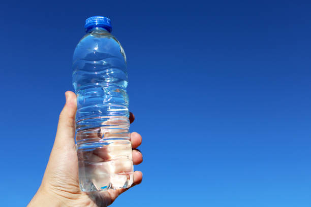 istock water in plastic bottle in man's hand on sky background 1496970498