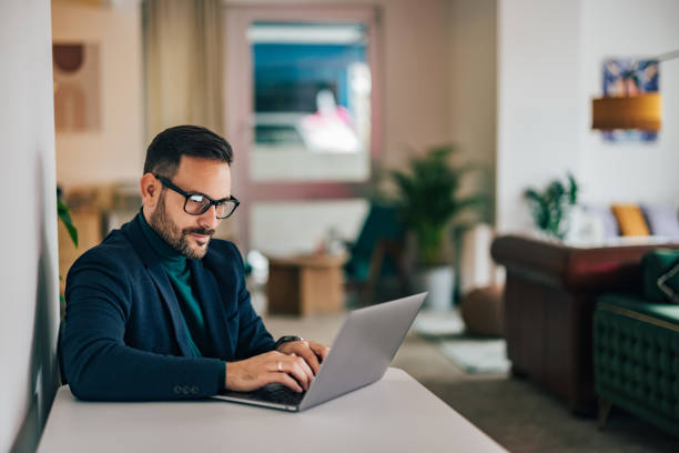 istock Serious businessman sitting at the home office, typing an email. 1496975968