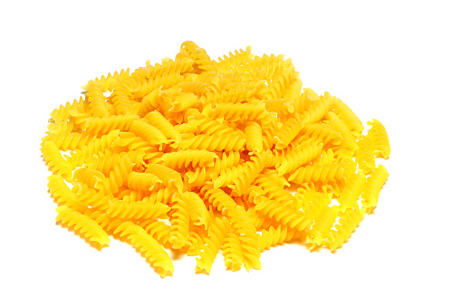 pile of spiral pasta scattered on light background. corkscrew shaped spiral pasta or fusilli pasta on white background
