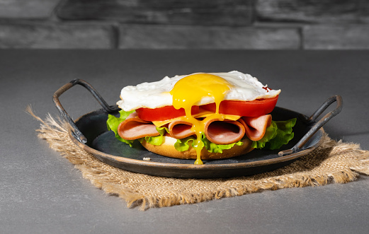 Sandwich with a fried egg, ham, cheese and vegetables.