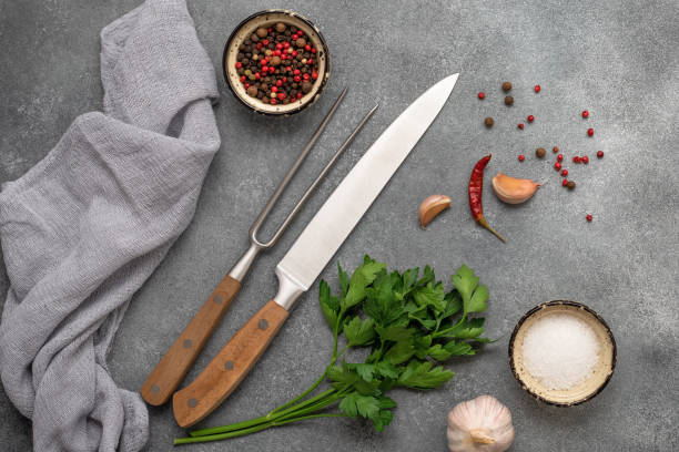 istock Cooking background, knife, meat fork, spices and greens. Gray concrete background. Top view, flat lay 1496979142