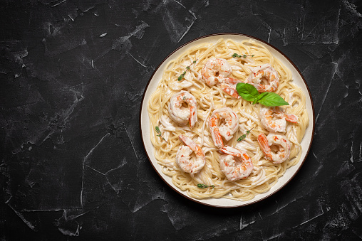 Shrimp Scampi with Pasta, black stone background. Top view, flat lay, copy space.
