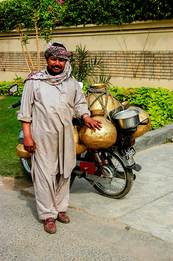 Pakistan, Lahor - March 27, 2005 : Milkman delivering milk on motorcycle in Lahore
