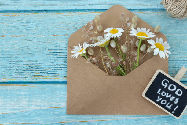 istock God loves you, handwritten message note on small blackboard and flowers with vintage envelope on wooden table 1496983492