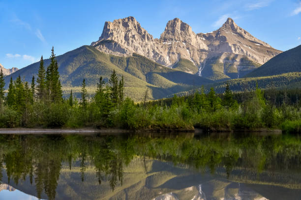 Panoramic view of the Three Sisters in Canmore, near Banff National Park in summer with sunset view over wilderness area panorama.