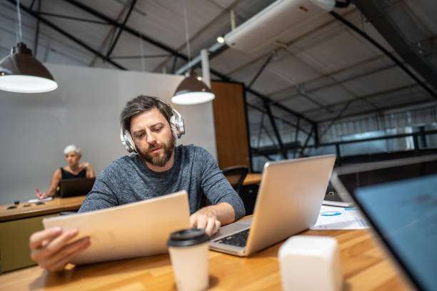 istock Mid adult businessman looking to a paper/document while use laptop at office 1496988023