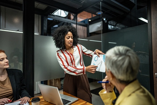 Young businesswoman showing a document/graph to her coworkers during a meet at office