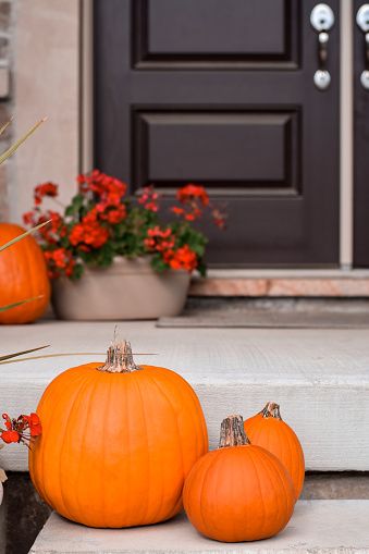 Orange pumpkins decorating front steps of house porch in Autumn for Halloween or Thanksgiving