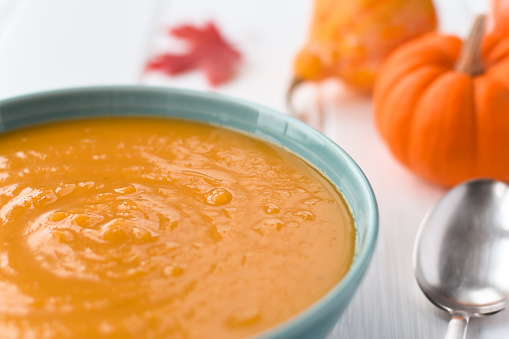 A bowl of pumpkin soup with mini pumpkins closeup