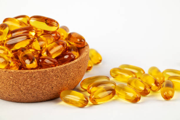 istock Cod liver oil omega 3 gel capsules in bowl on white background. 1496993580