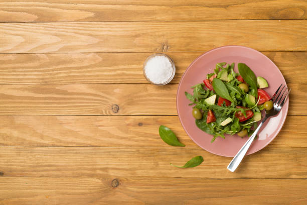 istock Fresh salad with arugula, spinach and vegetables on wooden background, top view 1496993590
