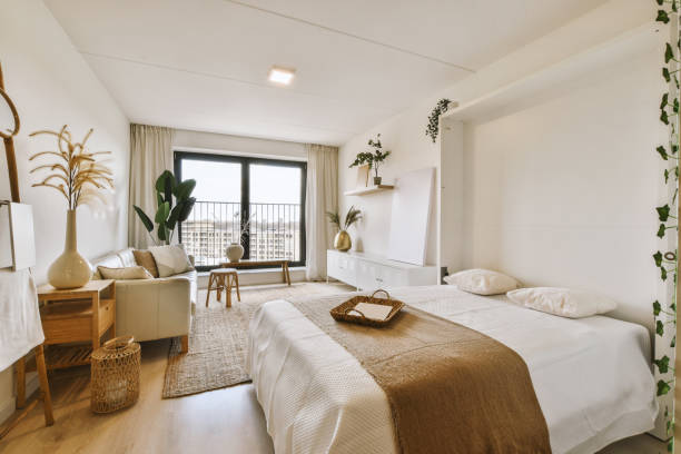 a hotel room with a bed, chair and window overlooking the cityscapea is on the right side