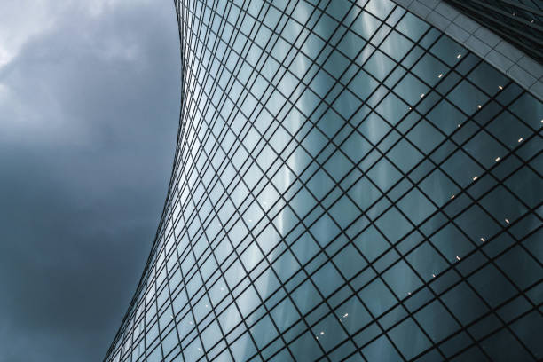 Modern building facade of glass and concrete reflecting clouds. Complex architectural pattern