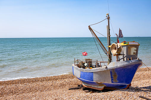 An active fishing boat pulled up onto the beach at Hythe in Kent, UK