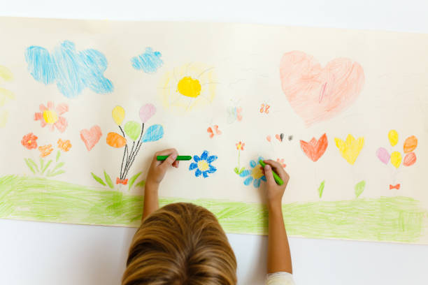 istock Little boy drawing with crayons on a paper roll sticked on the wall 1496998043