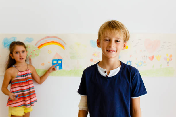 istock Children having fun drawing with crayons on a paper roll 1496998125