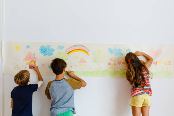 istock Children having fun drawing with crayons on a paper roll 1496998204