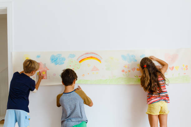 istock Children having fun drawing with crayons on a paper roll 1496998233
