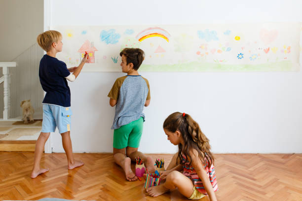 istock Children having fun drawing with crayons on a paper roll 1496998257