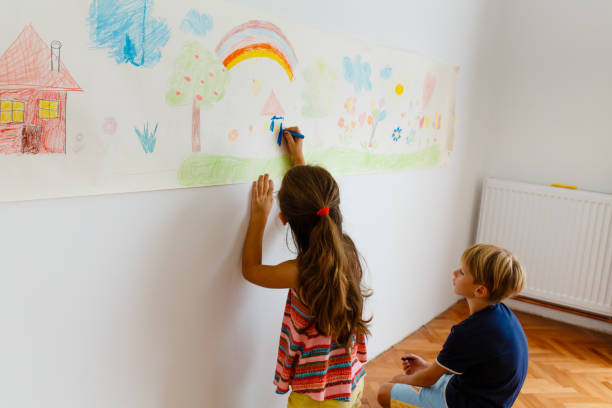 istock Children having fun drawing with crayons on a paper roll 1496998274