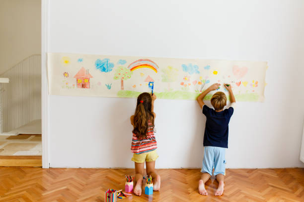 istock Children having fun drawing with crayons on a paper roll 1496998282
