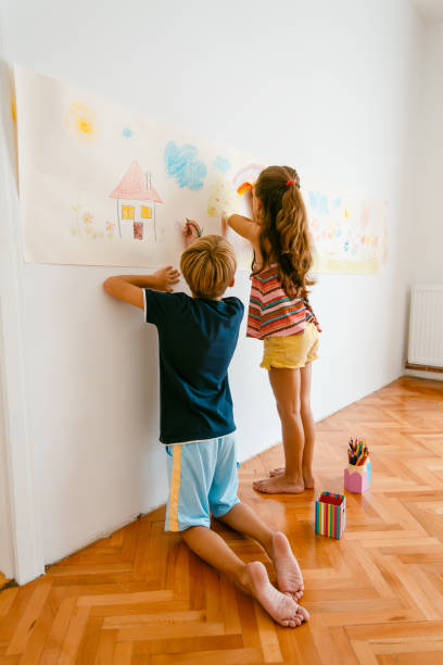 istock Children having fun drawing with crayons on a paper roll 1496998294