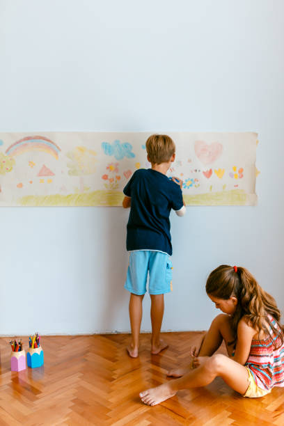istock Children having fun drawing with crayons on a paper roll 1496998370