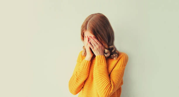 istock Upset sad crying woman covering her eyes with her hands while experiencing mental or physical suffering 1496999723