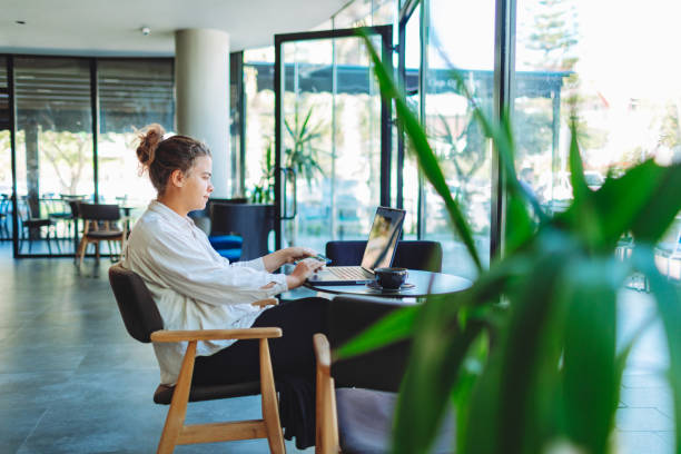 istock Young adult woman working from cafe using laptop 1497000675