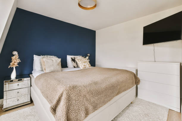 a bedroom with a bed and a blue accent wall - accent wall imagens e fotografias de stock