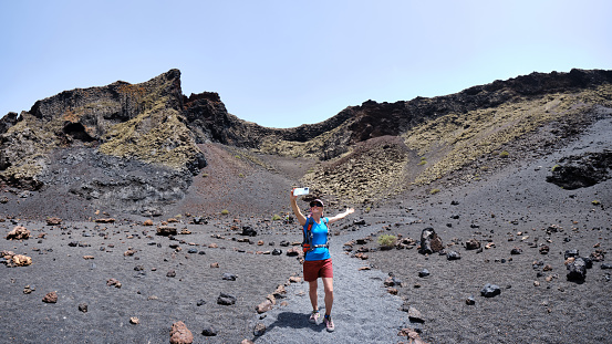 Woman taking a selfie inside the crater of El Cuervo volcano. Lanzarote. Canary Islands. Panoramic photo