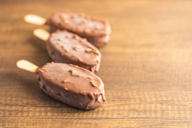 istock Popsicle, ice cream covered with chocolate on wooden table. 1497002682