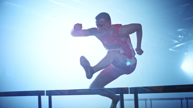 SLO MO TS Male athlete running over hurdles in competition