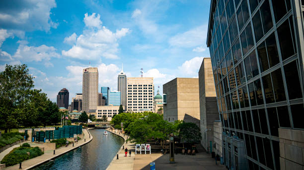 Indianapolis, Indiana, United States, seen from the Canal Walk near the Indiana State Museum. Downtown Indianapolis skyline with Central Canal in the foreground and the Indiana State Capitol Building in the distance.