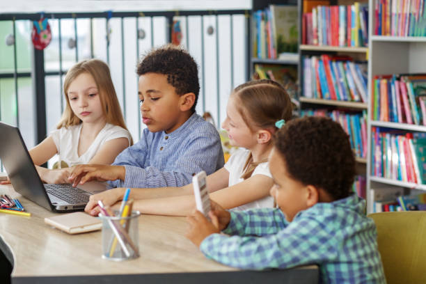 istock Side view at multiracial group of children sitting in row at school classroom and using laptops. 1497012460
