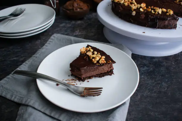 An eaten dark chocolate and hazelnut mousse pie on a white plate with a fork