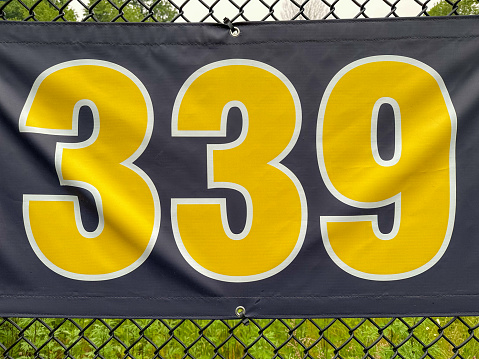 339 foot ft baseball field distance sign in yellow and black mounted on the black vinyl outfield fence.