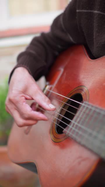Close-up of senior man hands playing acoustic guitar outdoors. Unrecognizable person rehearsing.