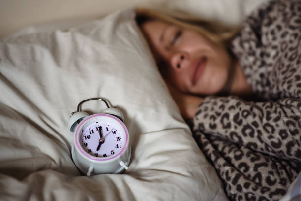 istock circadian rhythm, sleeping woman and alarm clock. 1497025429