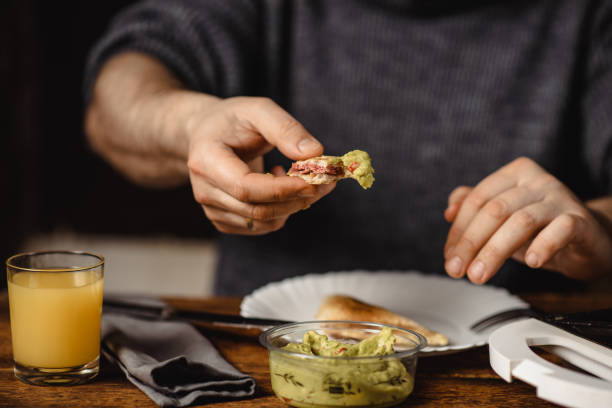 istock unrecognizable man eats toast with guacamole. Breakfast time. The man's hands are holding a toast. 1497025500