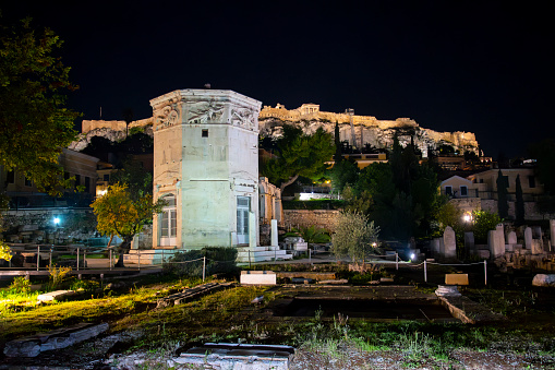 Night view of the illuminated Tower of the Winds at the ancient Roman Agora under the Parthenon and Acropolis Hill in the Plaka district of Athens, Greece.