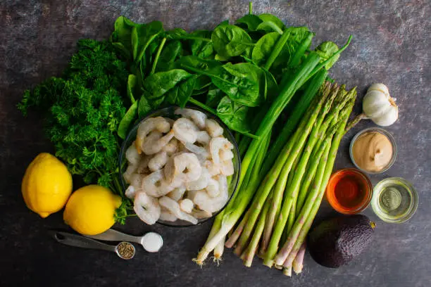 Ingredients for a healthy green salad with shrimp and lemony salad dressing