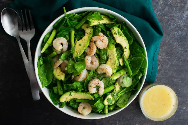 Healthy salad in a serving bowl with lemon vinaigrette salad dressing on the side