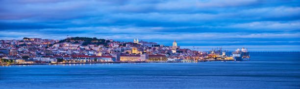 View of Lisbon view over Tagus river with yachts and boats in the evening. Lisbon, Portugal View of Lisbon over Tagus river with passing ferry boat from Almada with moored cruise liner in evening twilight. Lisbon, Portugal national pantheon lisbon stock pictures, royalty-free photos & images