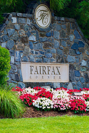Fairfax, Virginia, USA - July 8, 2023: An entrance sign enhanced by colorful flowers and plants welcomes visitors to the “Fairfax Corner” shopping, dining, entertainment, and residential complex in Northern Virginia.