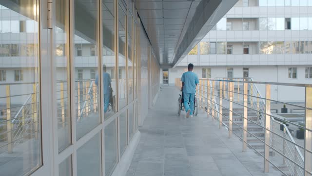 Doctor with nurse walking outside hospital building and discussing