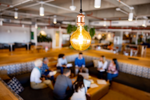 Group of business people sharing ideas in a creative meeting at the office - focus on a lightbulb