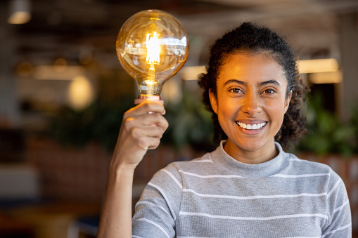 Portrait of a creative African American female entrepreneur having an idea and holding a light bulb