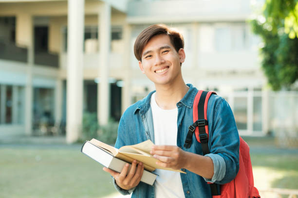 Student standing outdoor and holding books. stock photo